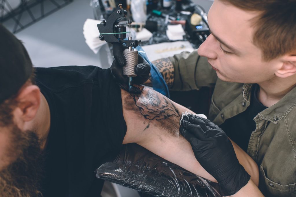 Inicio 10 bearded-man-and-tattoo-master-during-tattooing-process-in-studio-e1631513027875.jpg